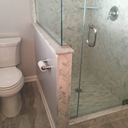 Master Bathroom Renovation with marble shower tile, wood-look tile, frameless shower door, knee wall to separate toilet