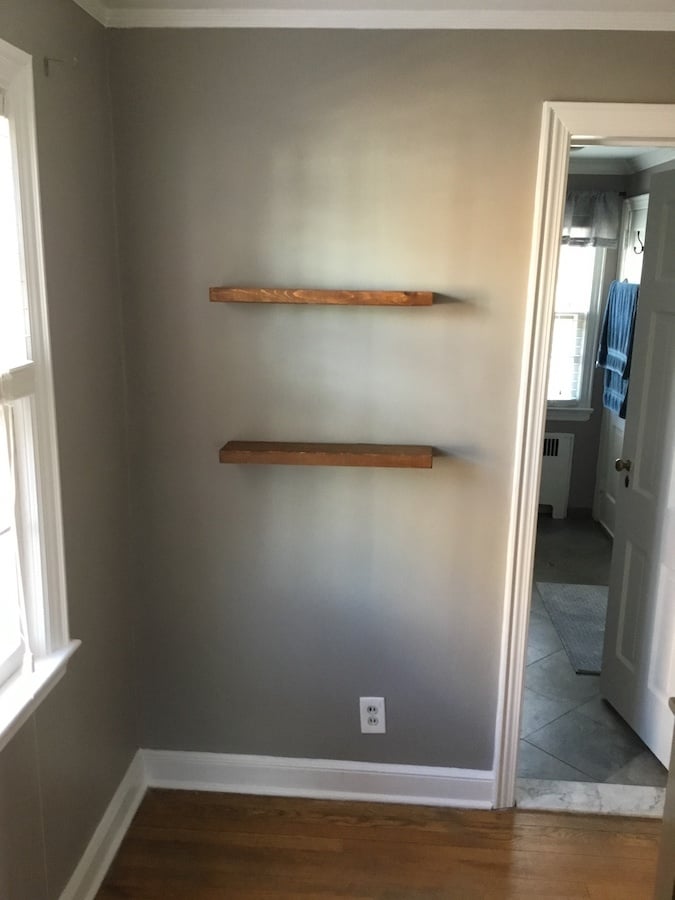 Floating shelves installed over freshly painted wall