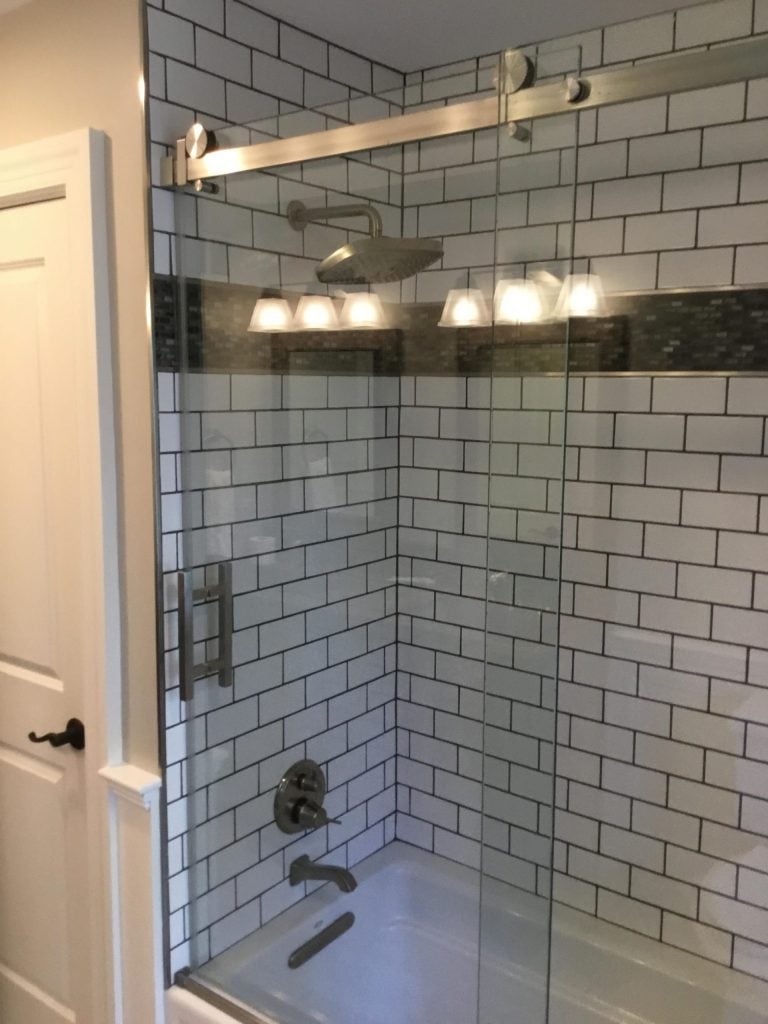 Remodeled Shower with Dark Grout and Glass Shower Door
