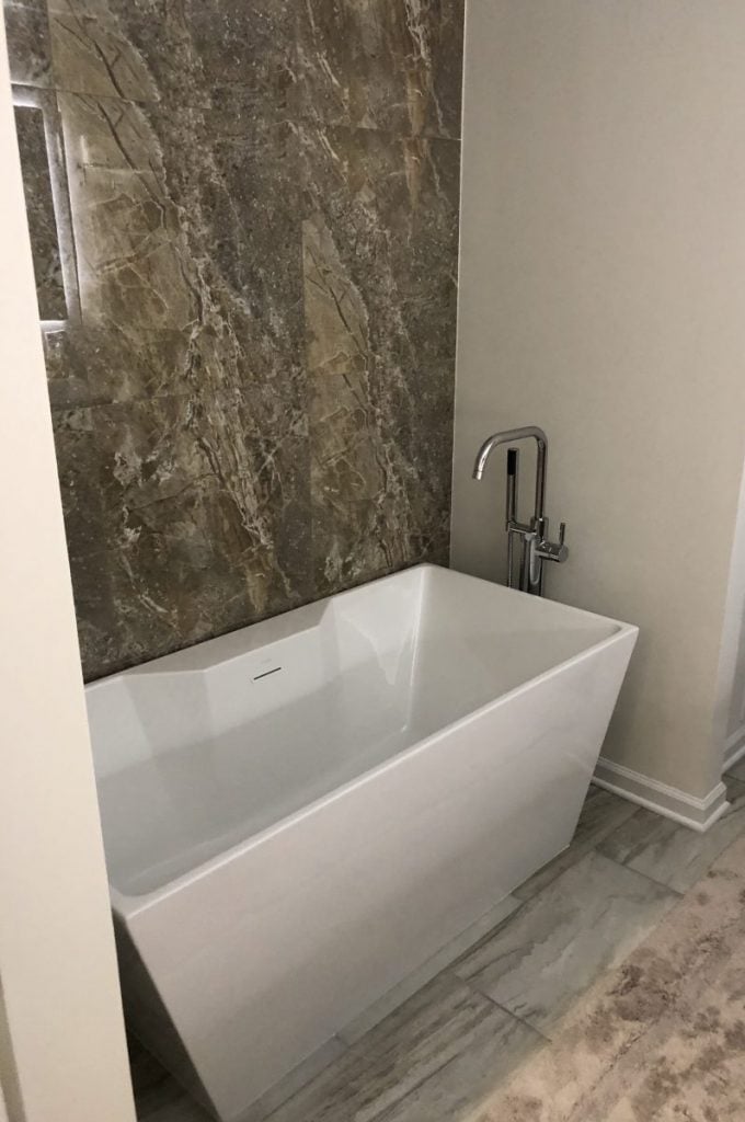 Large granite wall tile behind tub